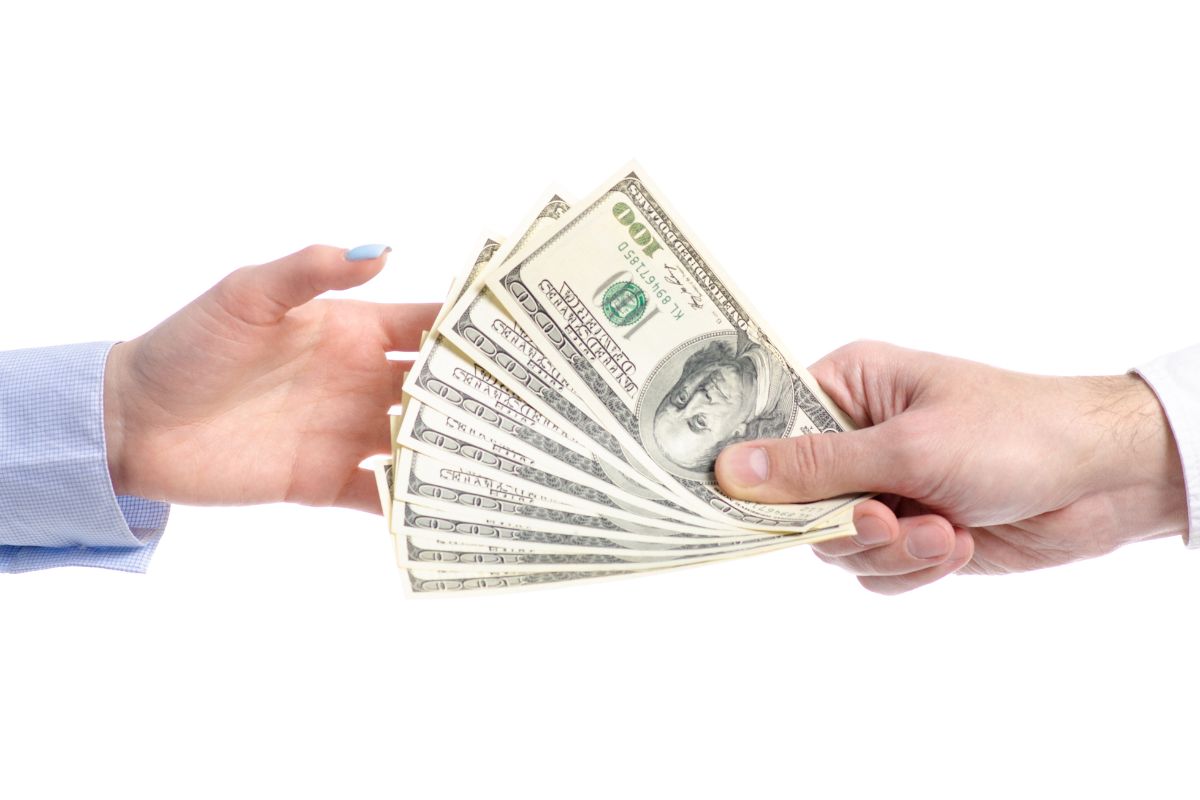 An image of a man's hand lending his money.