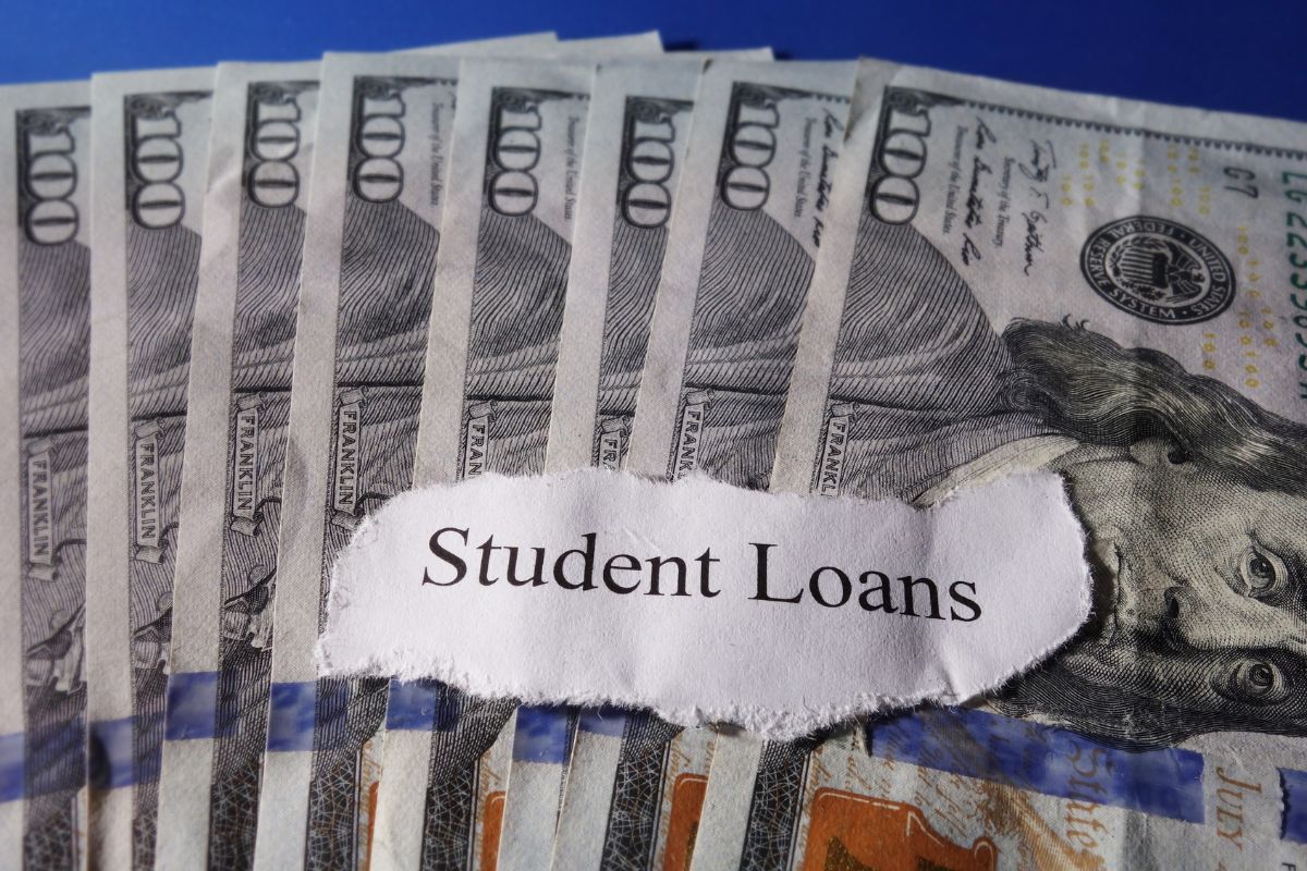 A picture shows money and student loans wording on paper.