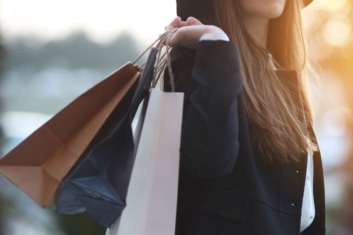 An image shows a young lady carrying shopping bags.
