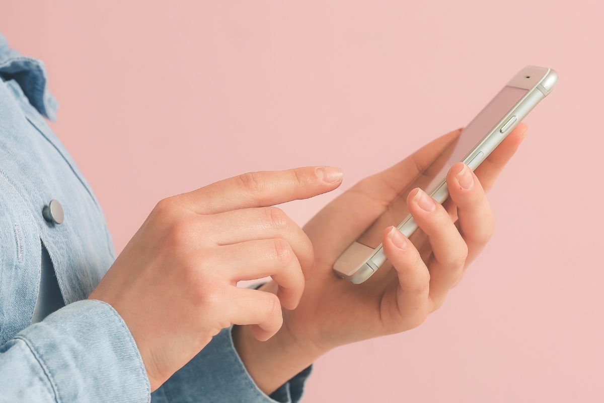 An image shows a lady's hand using a phone.
