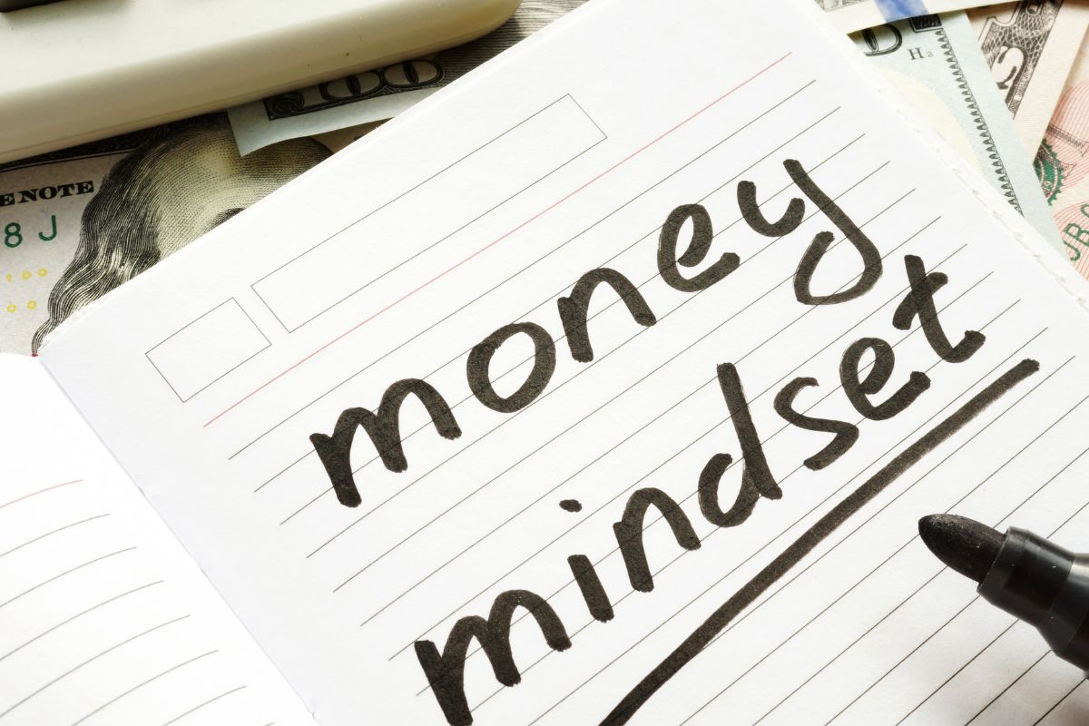 A picture shows a notebook with money mindset wording.