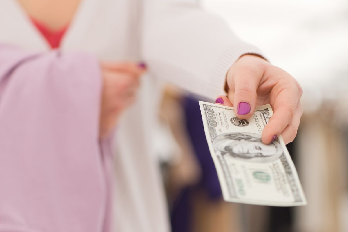 An image shows a woman paying with cash.
