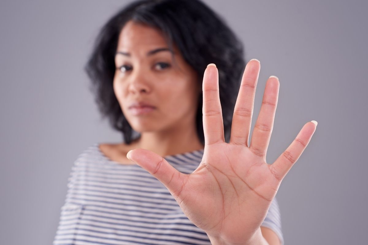 An image shows a woman doing a stop sign.
