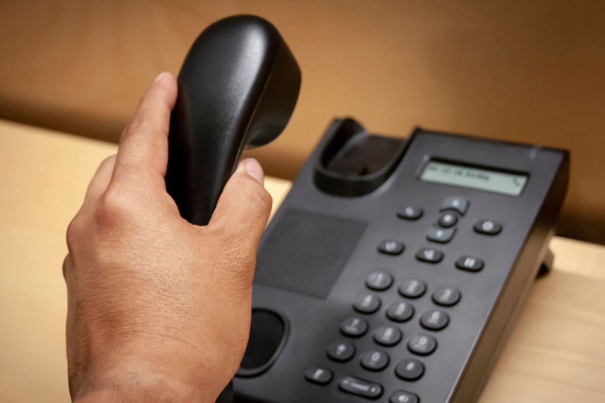 A picture of a woman's hand hanging up the phone.