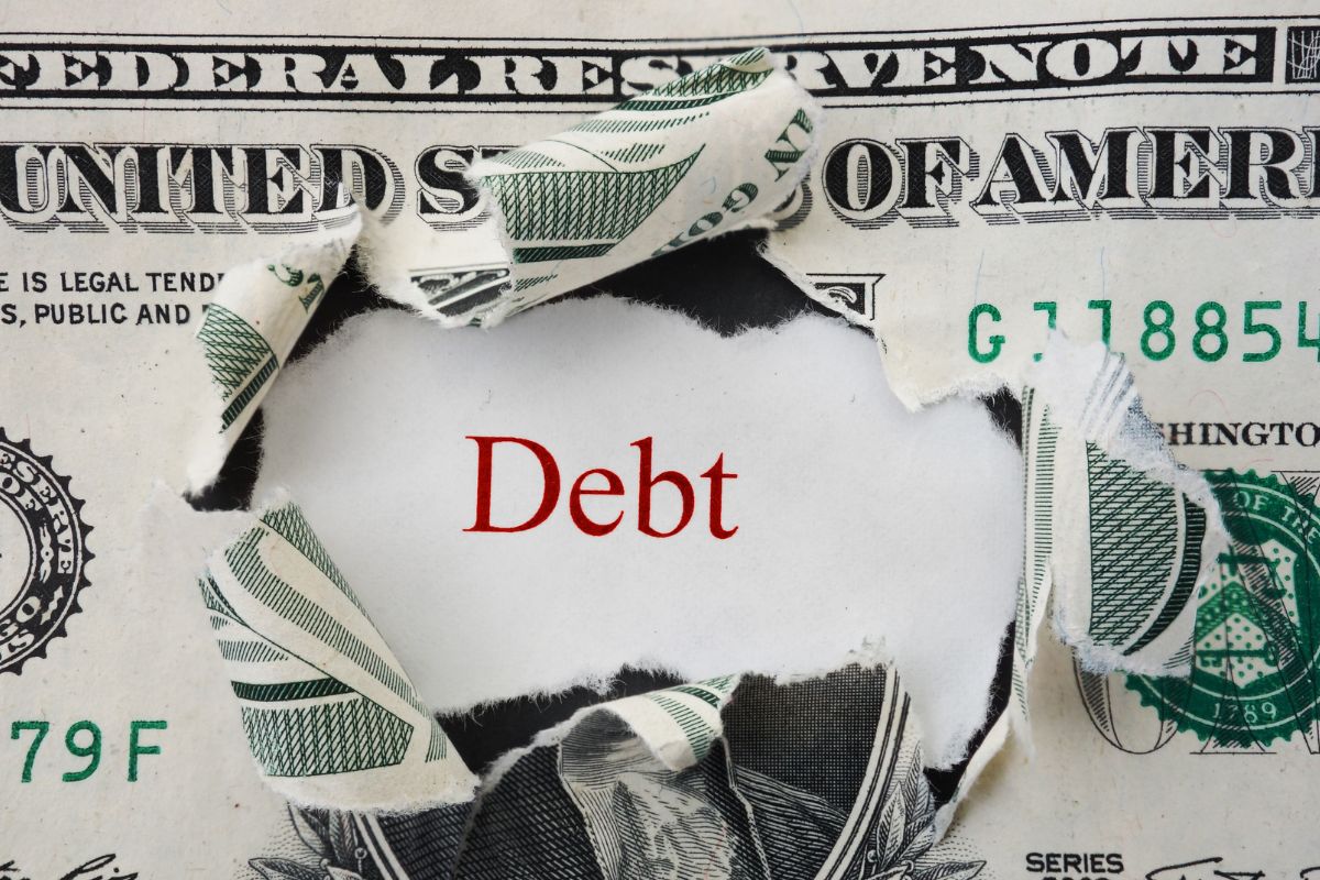 A picture shows torn money and the word debt.