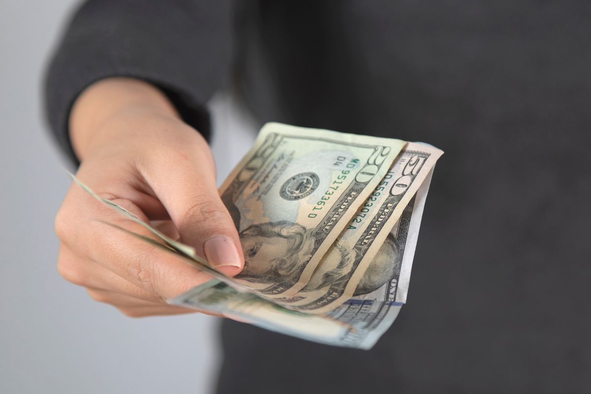 An image shows a woman's hand holding money.