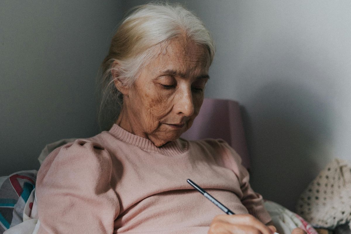 A picture of an elderly woman writing something.