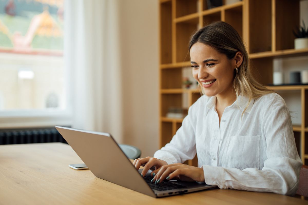 A picture of someone smiling while using their laptop.