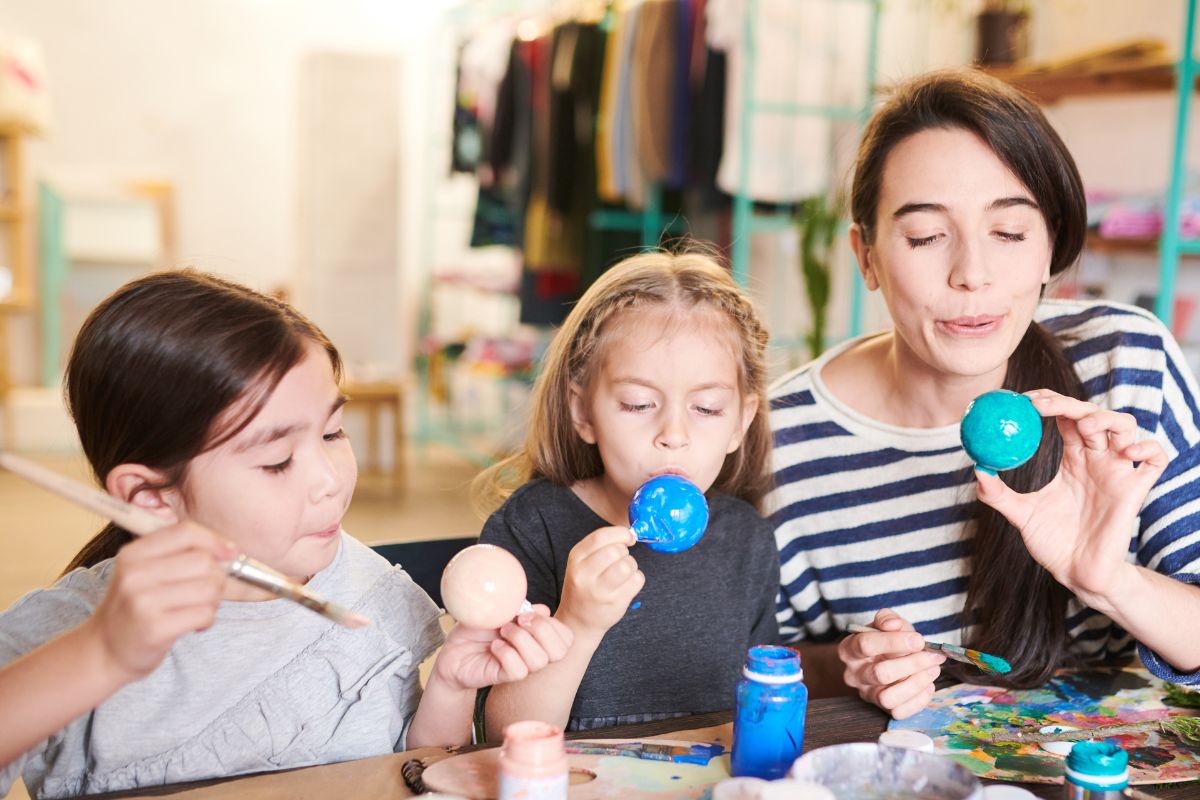 A picture of a mom and her kids making decor.