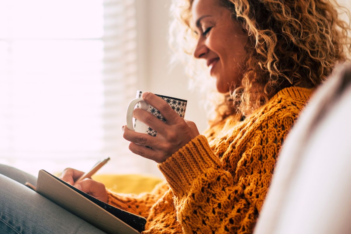 A picture of a smiling woman taking notes.