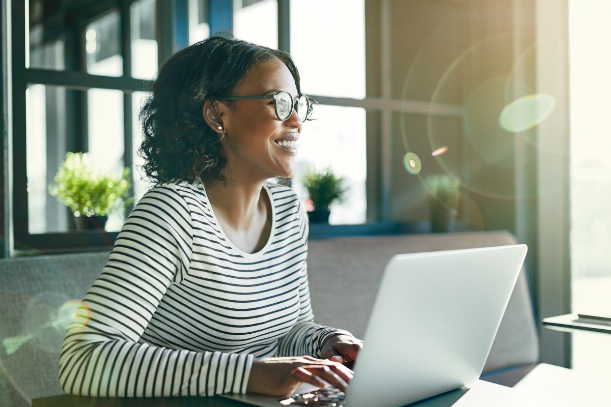 A picture of someone using their laptop while smiling.