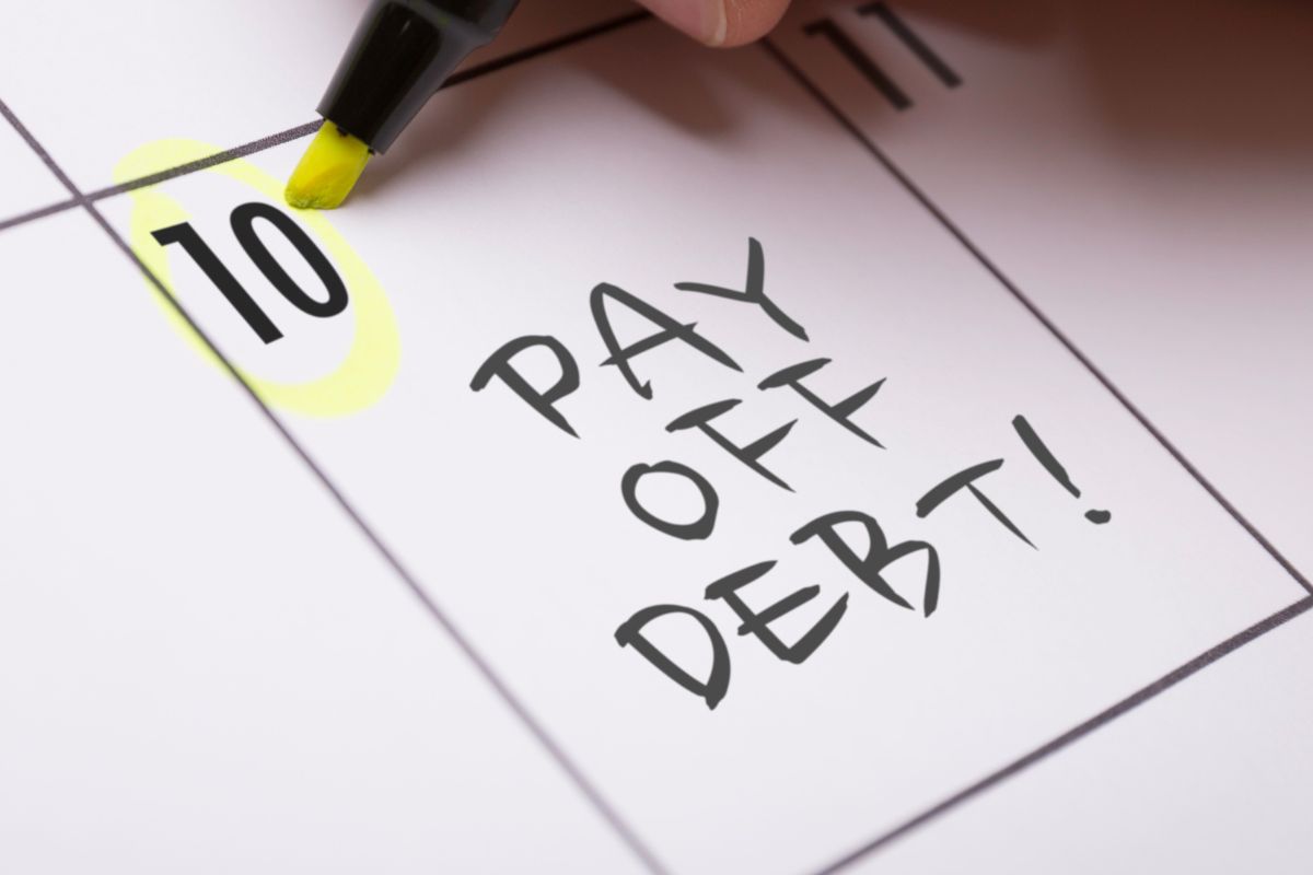 A picture of a note with "pay off debt" on it.