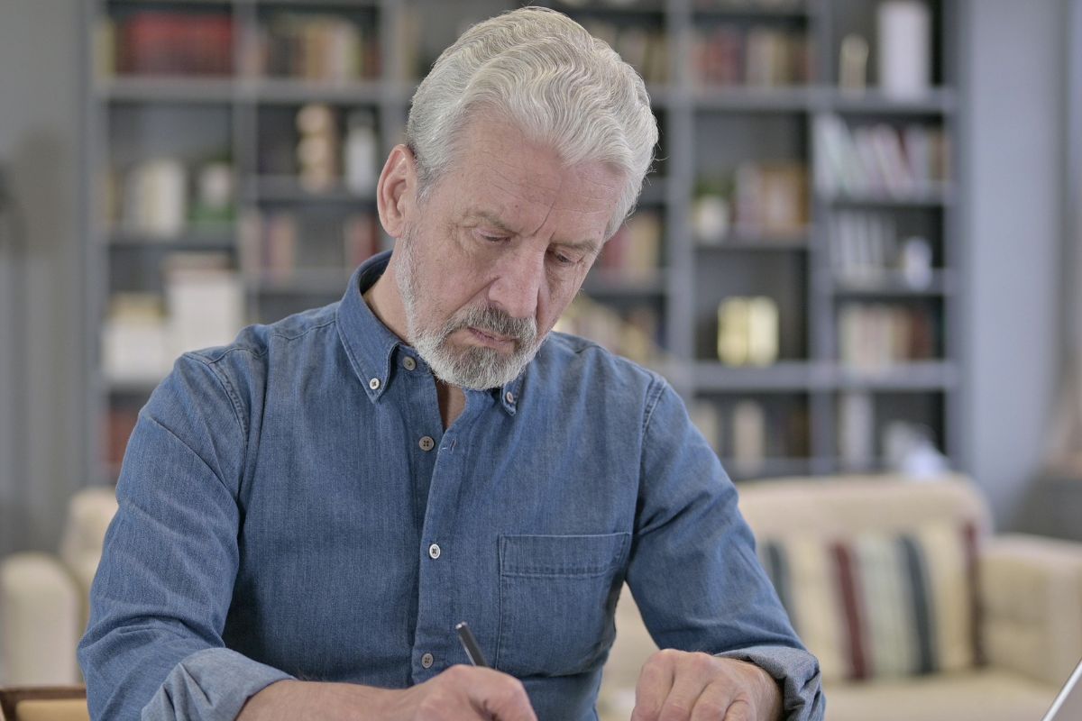 A picture of an elderly person writing something.