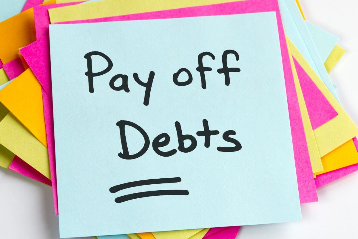 A picture of a post-it with a note saying "Pay off Debts".
