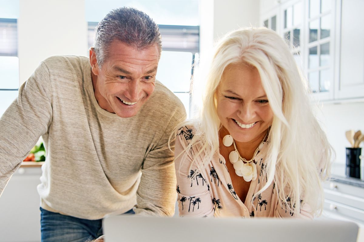 A picture of a couple smiling while using their laptop.