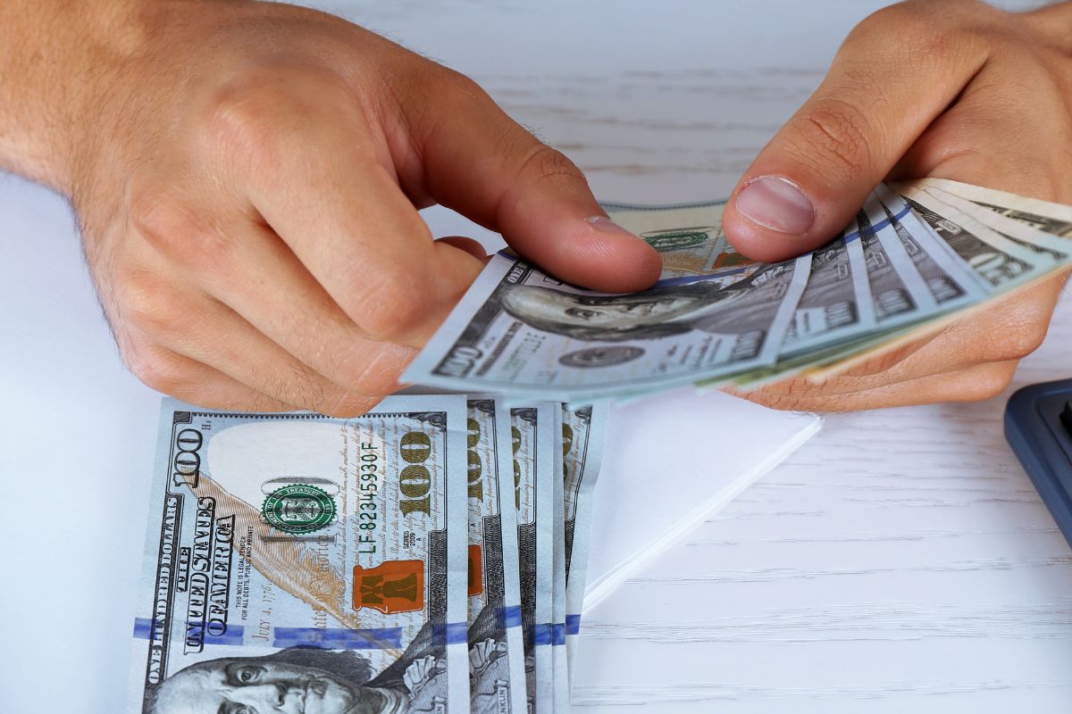 An image shows a man's hand counting money.