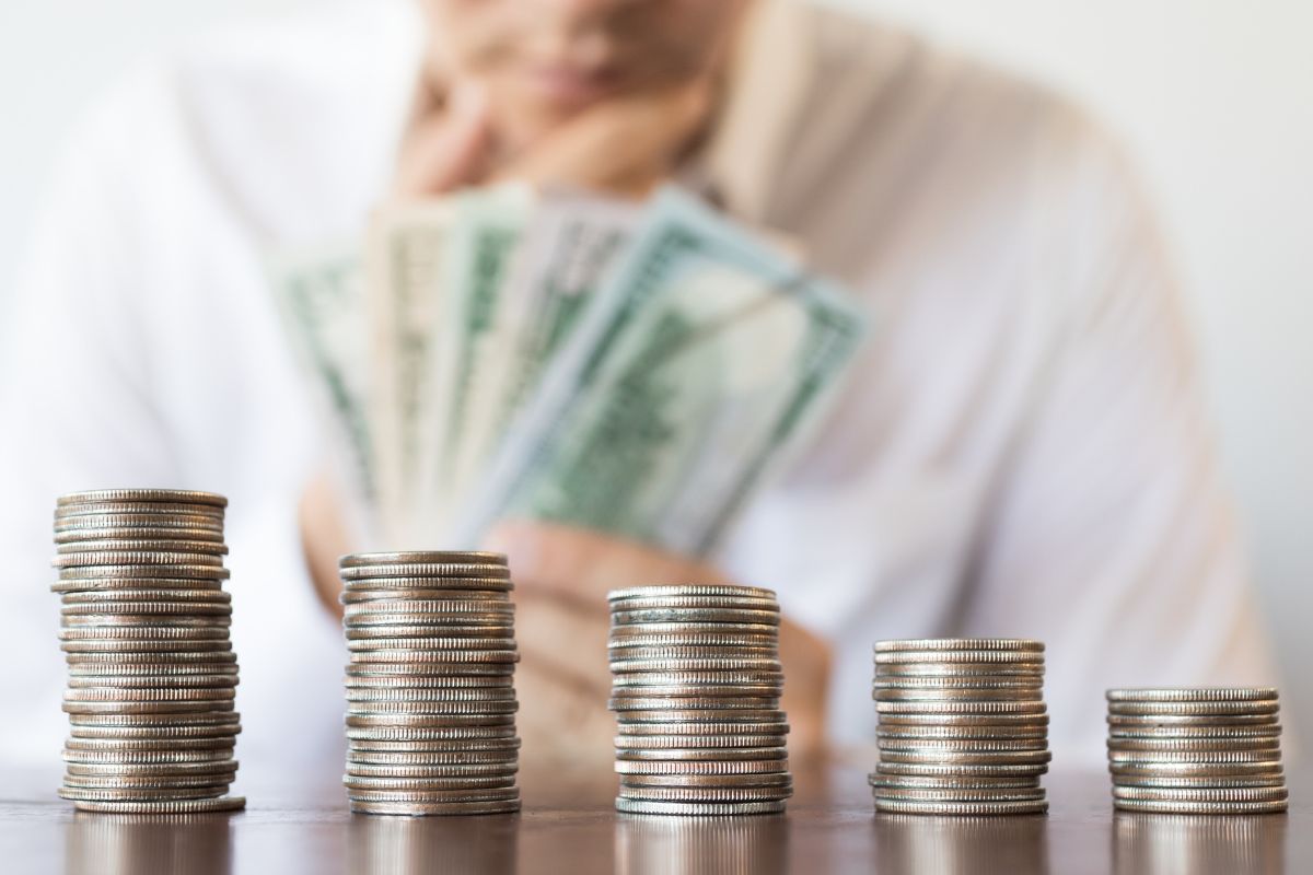 A picture of a stack of coins and a man holding money.