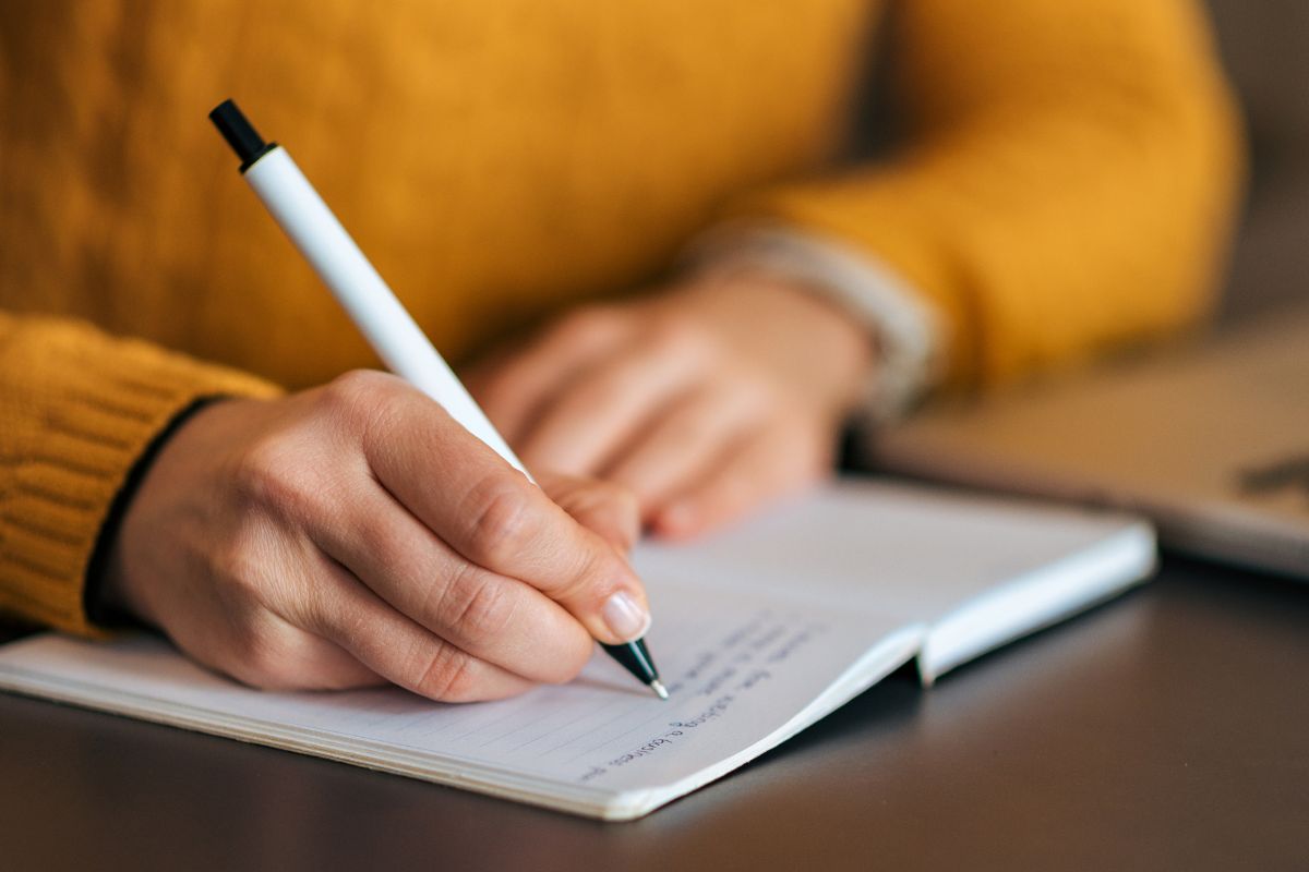 A picture of a woman writing in a notebook.