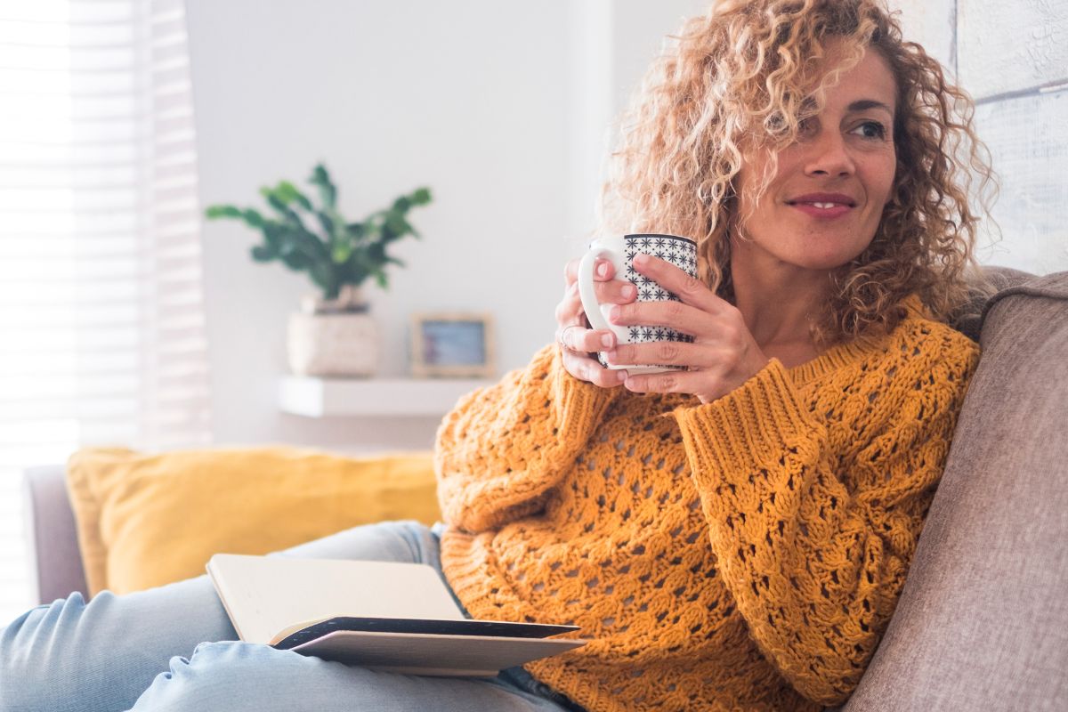 An image of a woman sitting on the couch while having a coffee.