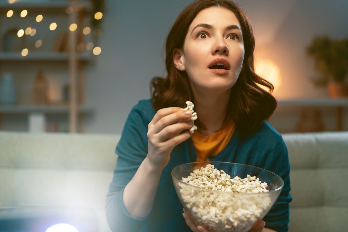 A picture of a woman watching a movie while eating popcorn.