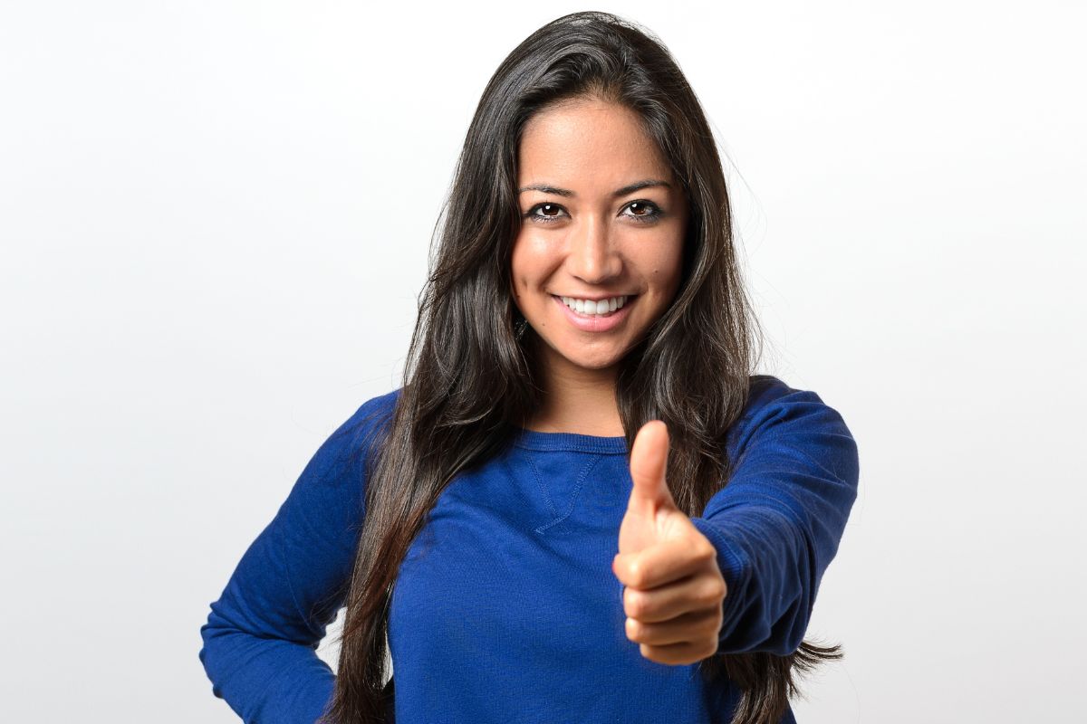 An image shows a woman doing an ok sign.
