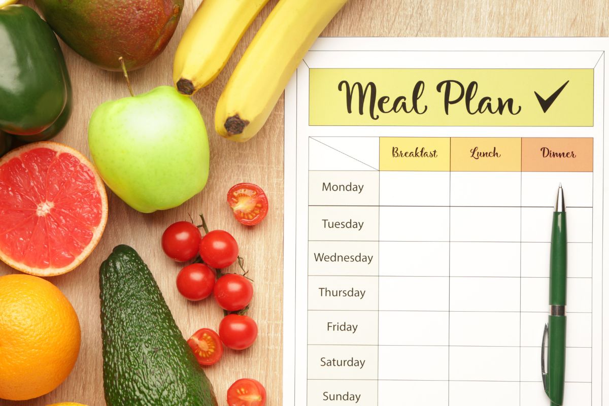 An image shows fruits and a meal plan paper.