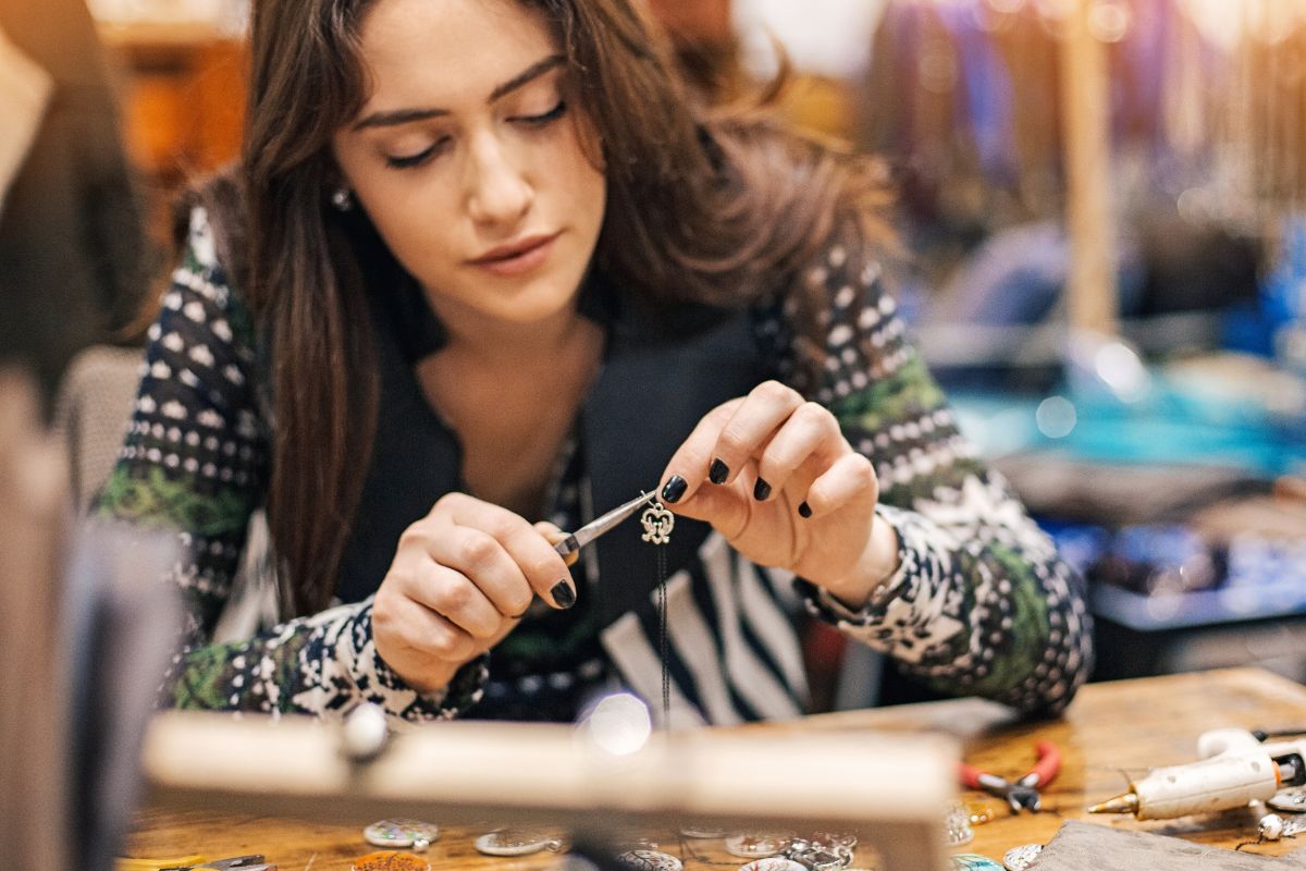 A picture shows a woman crafting a necklace.