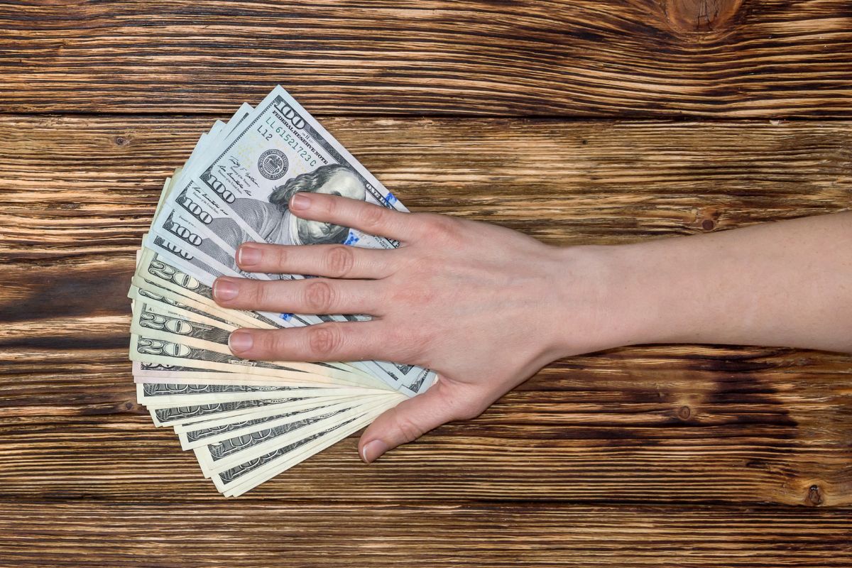 A picture shows a woman's hand holding money.