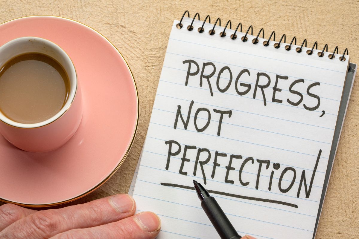 Une image montre un carnet avec le texte progrès, pas perfection.