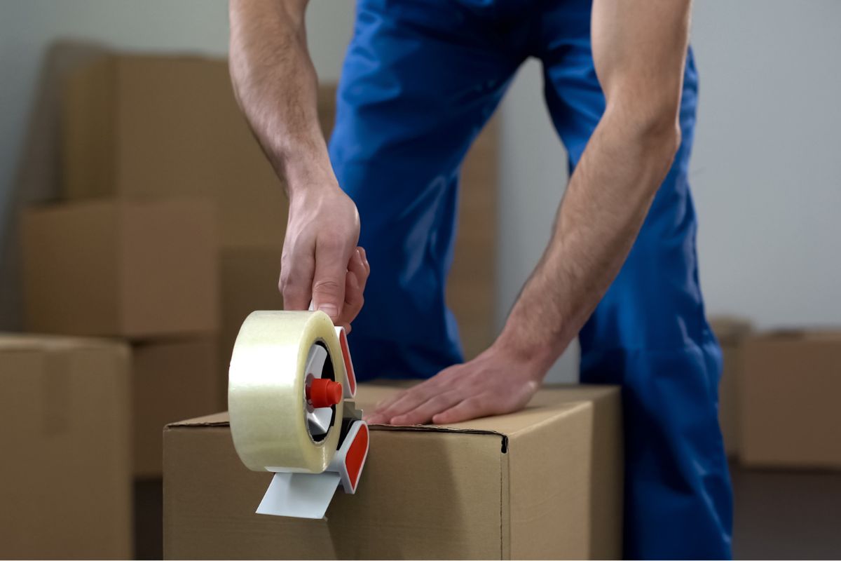 Un homme scotchant une boîte.