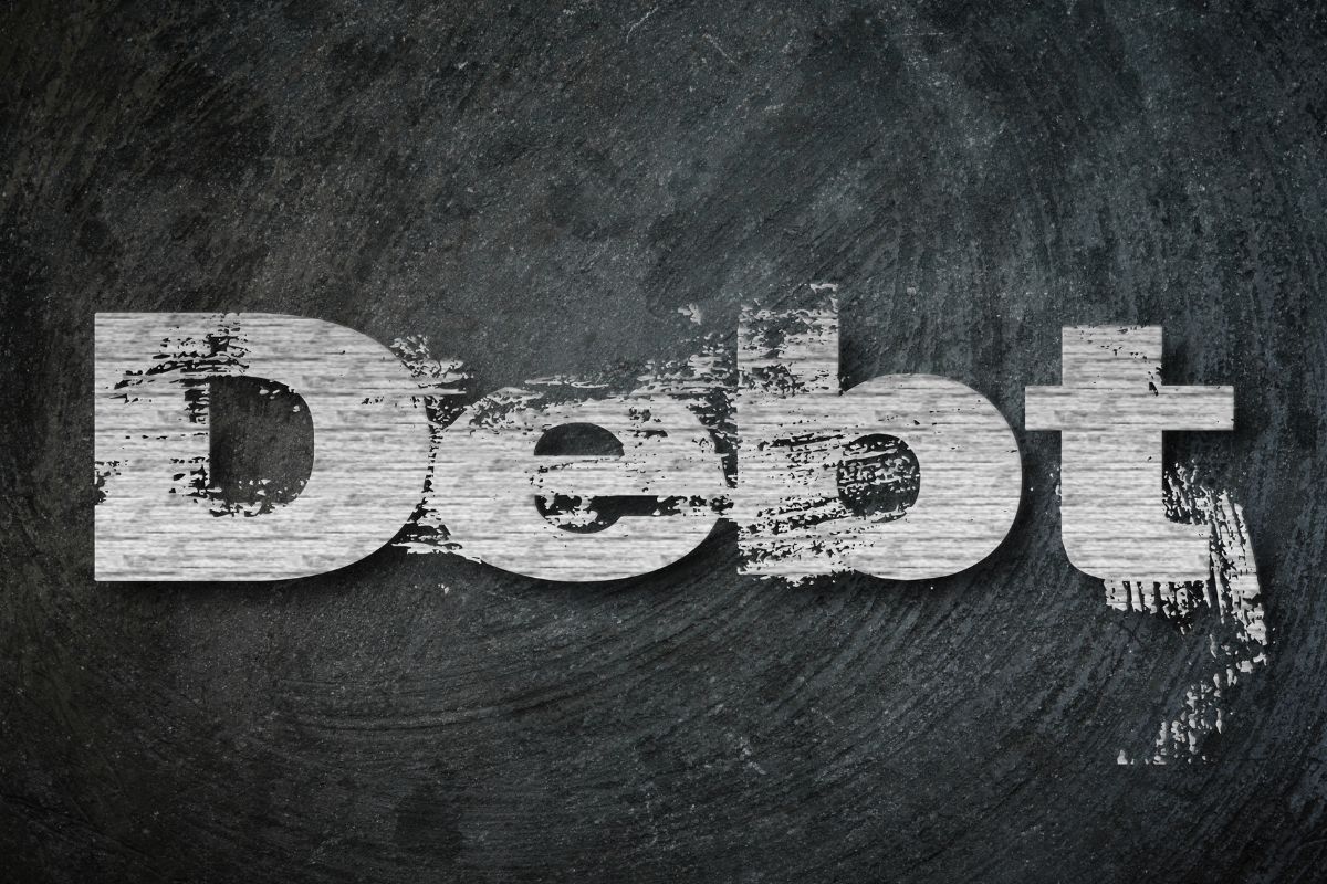 A picture shows a wall with debt wording.