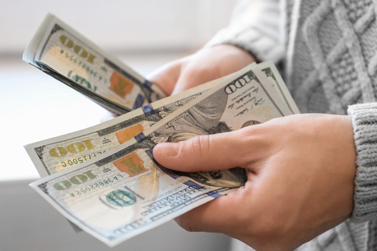 An image shows a woman's hand counting money.