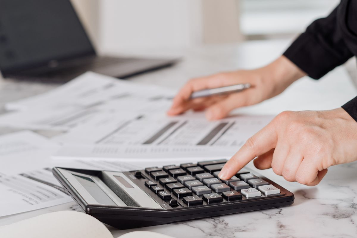 An image shows a man's hand calculating.