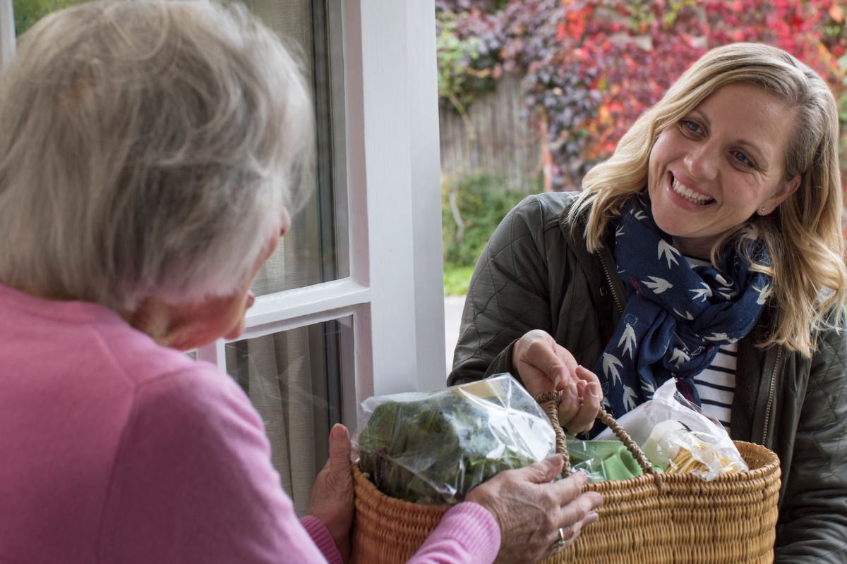 Une femme aidant son voisin avec des courses.