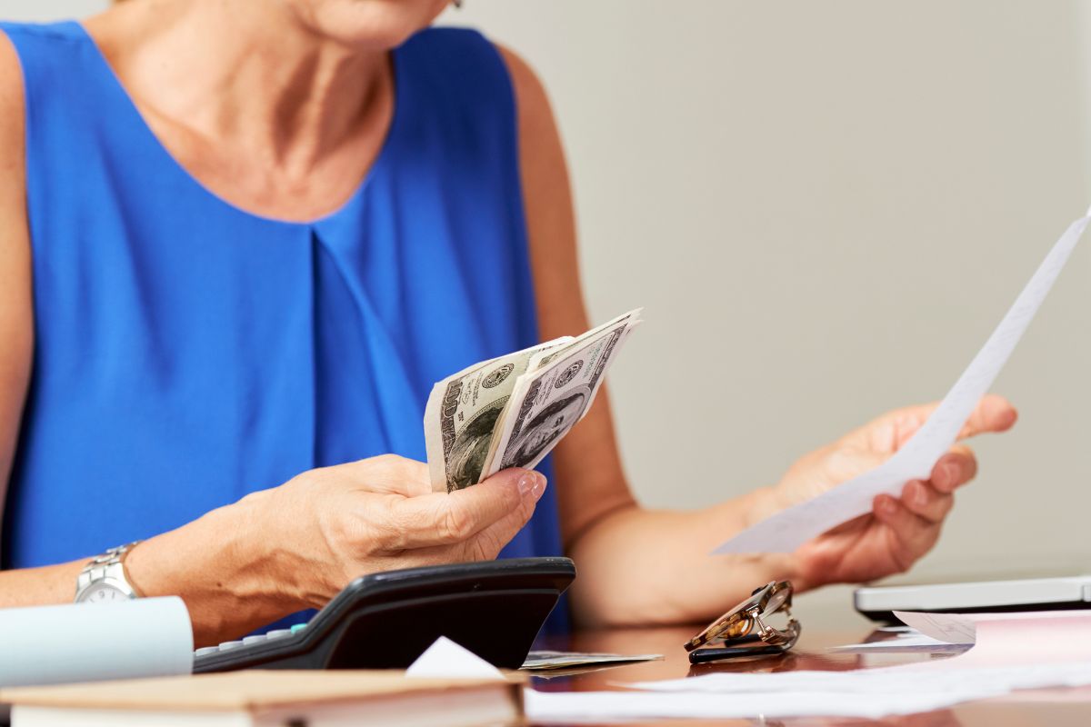 An image shows a woman holding money and a paper.
