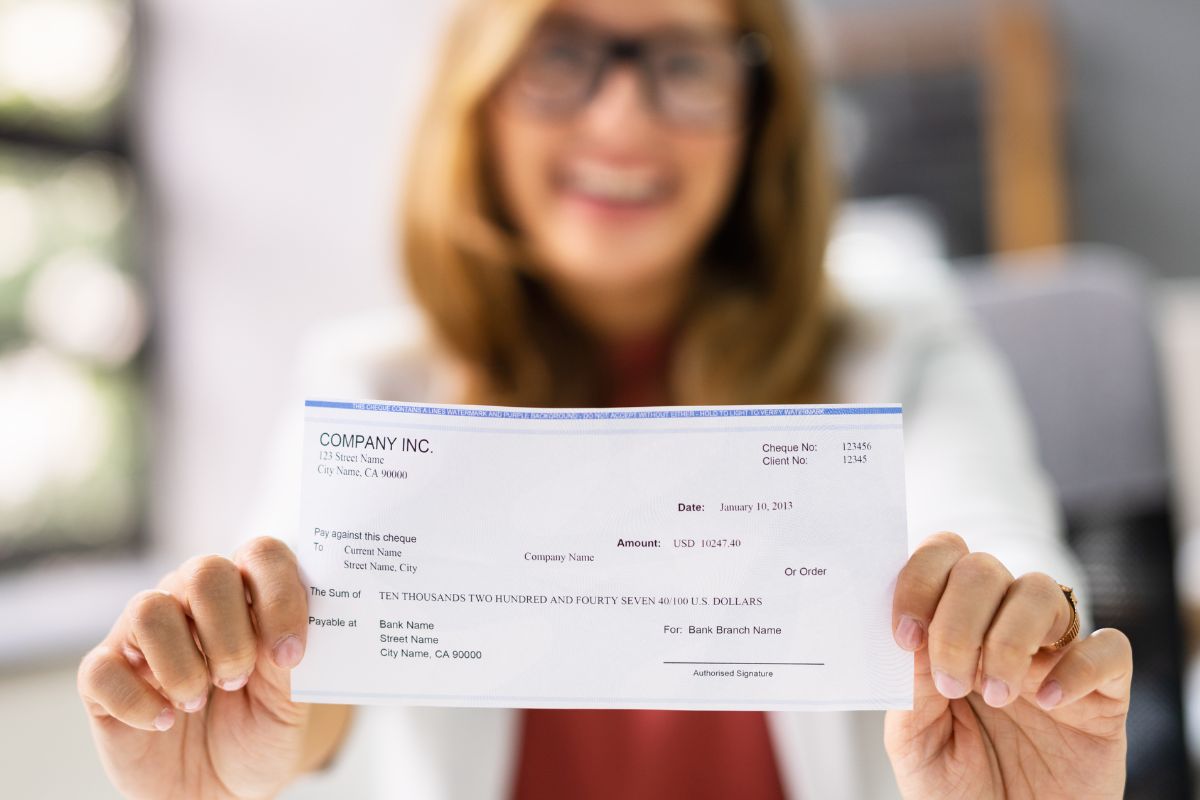 A picture shows a woman holding a paycheck.
