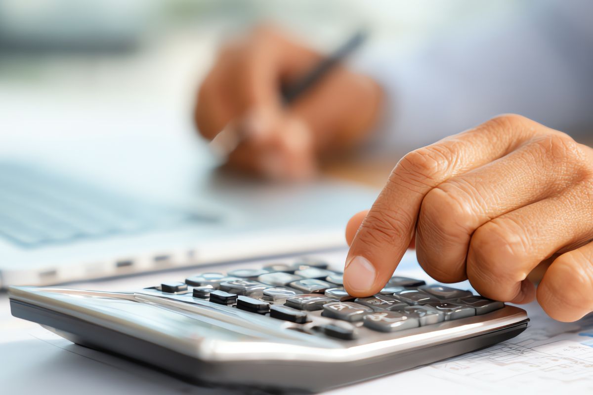 A picture shows a man's hand using a calculator.