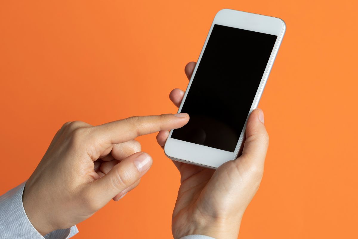 An image shows a man's hand using a phone.