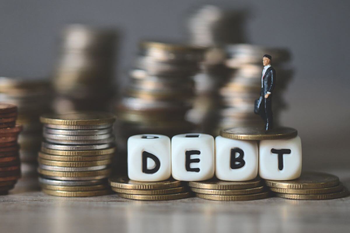 A picture of stacks of coins and debt wording.