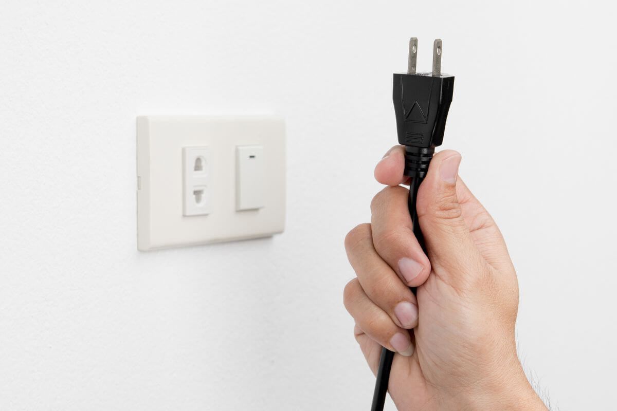 An image of a woman's hand unplugging an outlet.