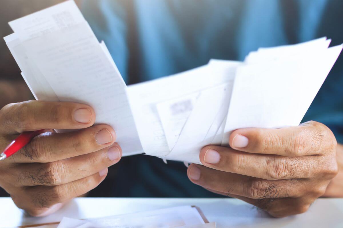An image of a man's hand reviewing papers.