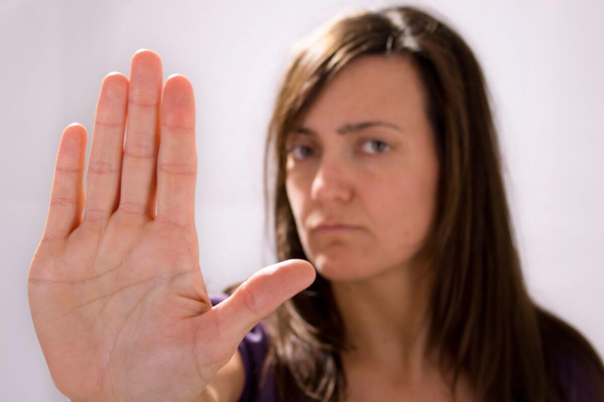 A picture of a woman doing a stop sign.