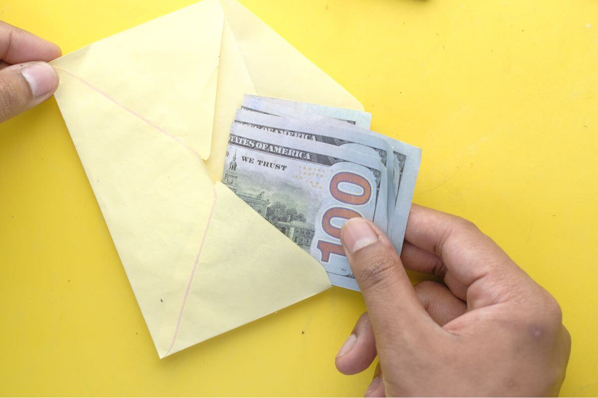 A picture shows a man's hand holding an envelope with money.