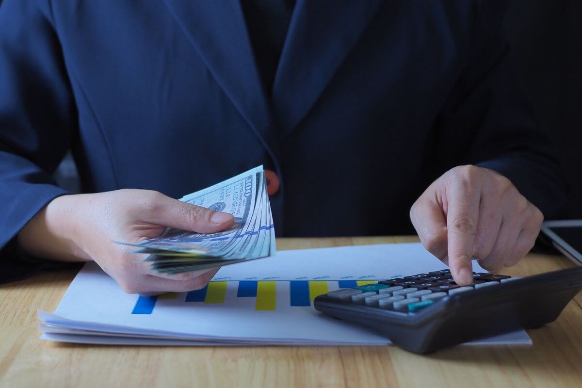An image shows a woman calculating money.