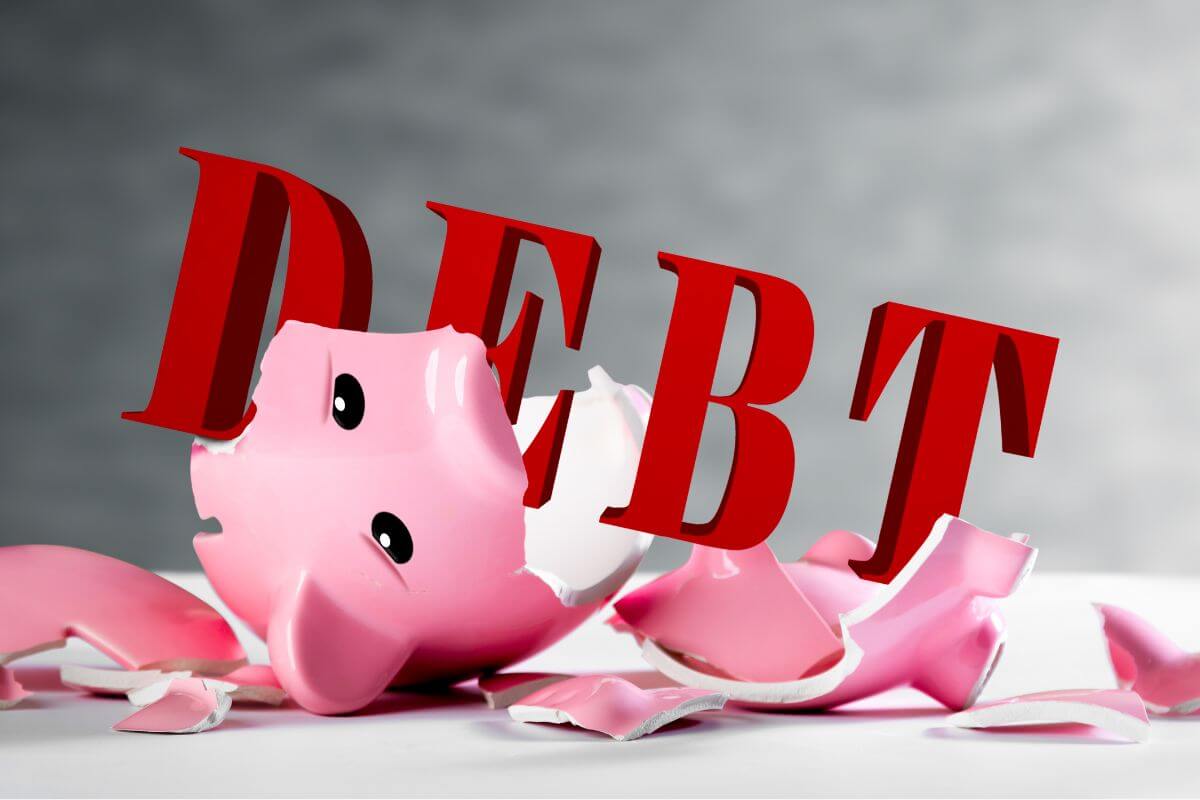 A picture shows a broken piggy bank and a debt word.