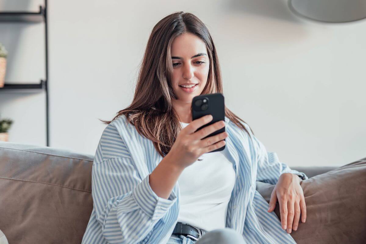 A picture of someone sitting while using their phone.