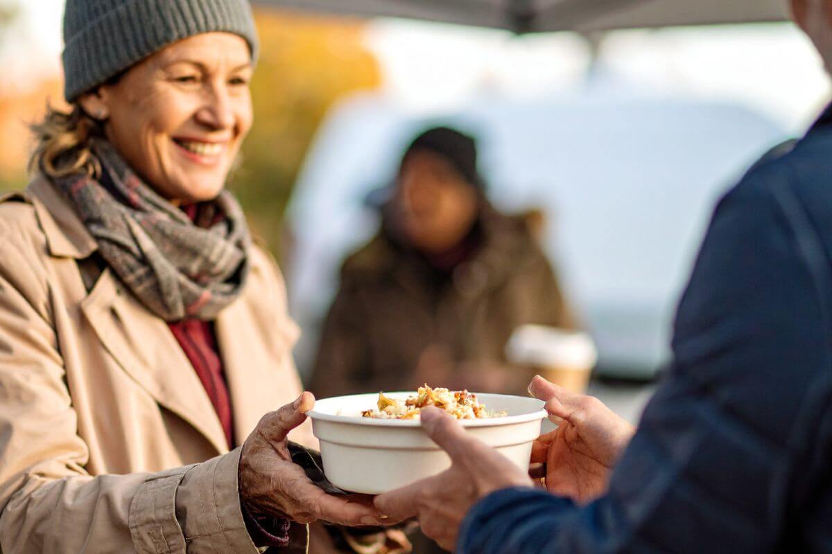 A picture of someone giving out food to the homeless.