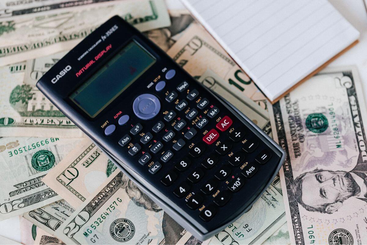 A picture of a calculator, a notepad, and wads of cash.