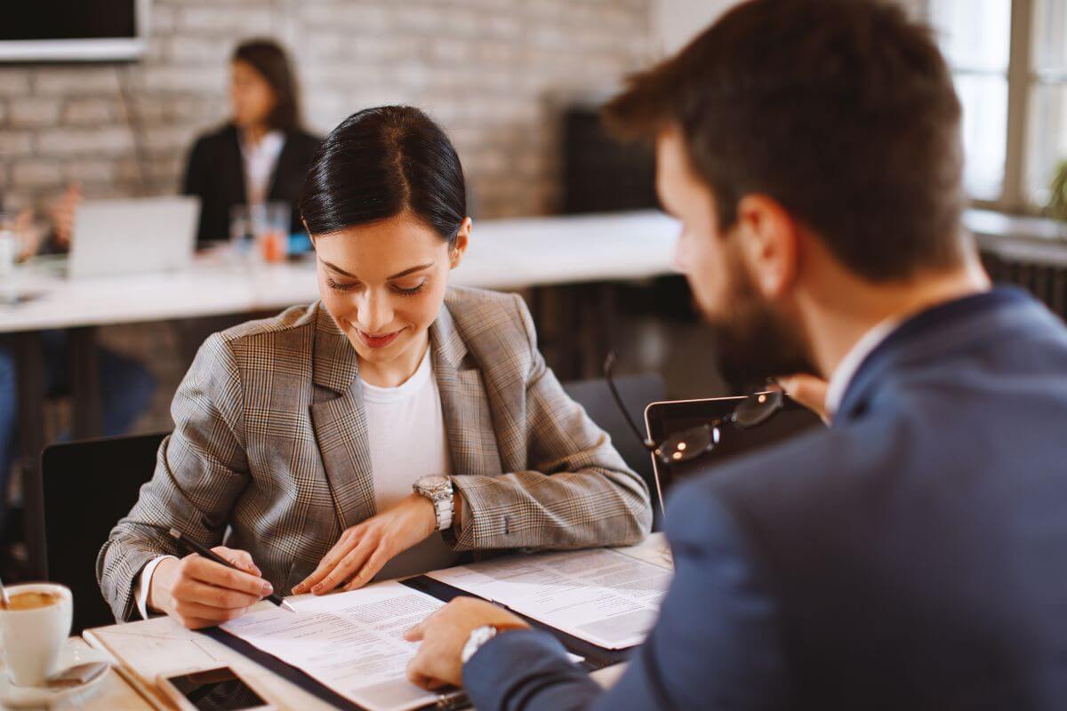 A picture of a woman signing a paper.