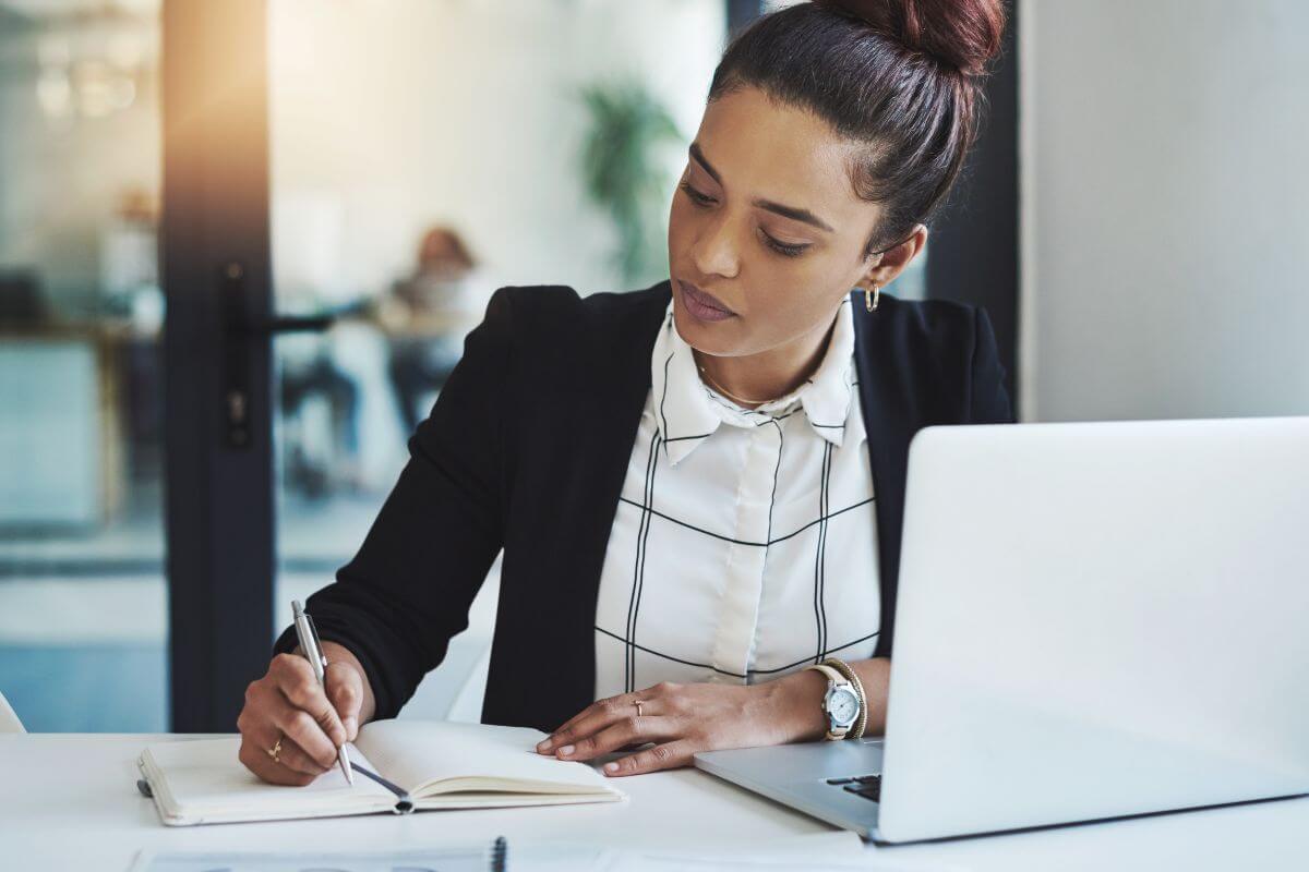 A picture of a woman writing in a notebook.